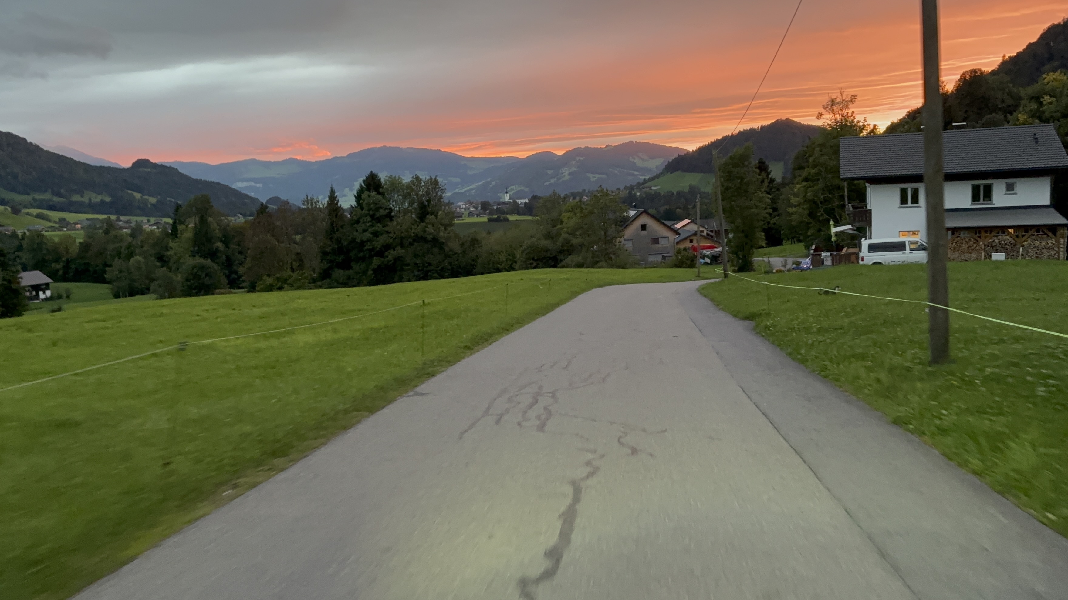 Straße durch eine Alpenlandschaft bei Abendlicht