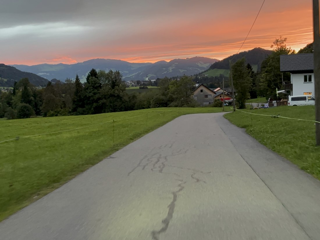 Straße durch eine alpine Landschaft bei Abendlicht